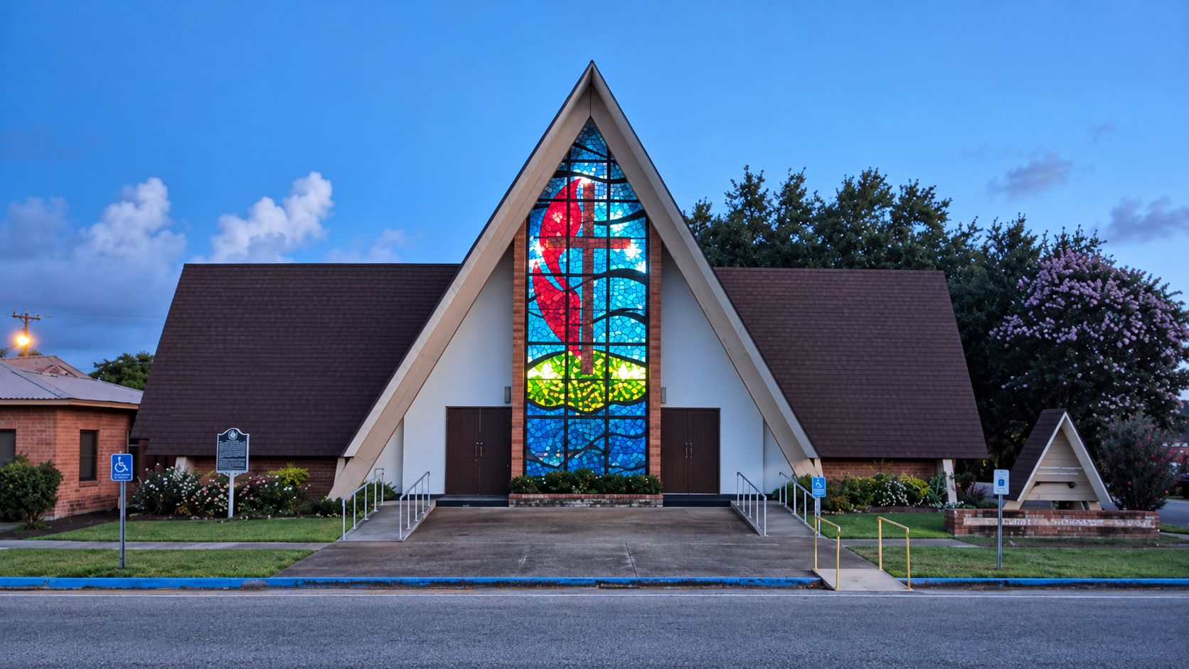 First UMC Palacios at dusk, its stained-glass cross illuminated